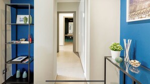 A hallway with a blue wall, a framed picture, and a potted plant on a console table. - Bluechiaia apartment- close to everything. (Napoli)