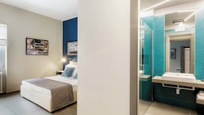 A bedroom with a bed, bedside table, and a nightstand. The room has a window, a framed picture on the wall, and a light source above the bed. - Bluechiaia apartment- close to everything. (Napoli)