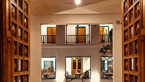 A courtyard with a wooden gate, a swing, and a small garden area. - Arch The Baakhli Resort (Ramnagar)