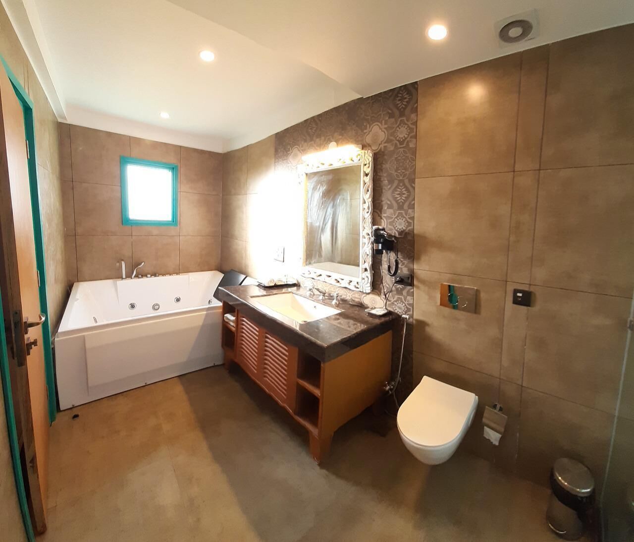 A modern bathroom with a bathtub, a sink, a toilet, and a large mirror.