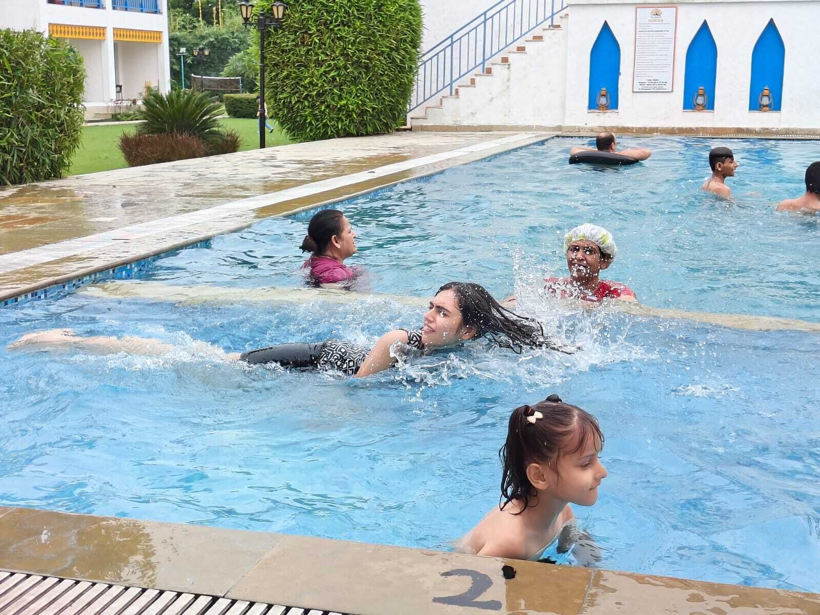 Una piscina con diverse corsie, circondata da un edificio bianco con dettagli blu e una scala che conduce a un livello superiore.