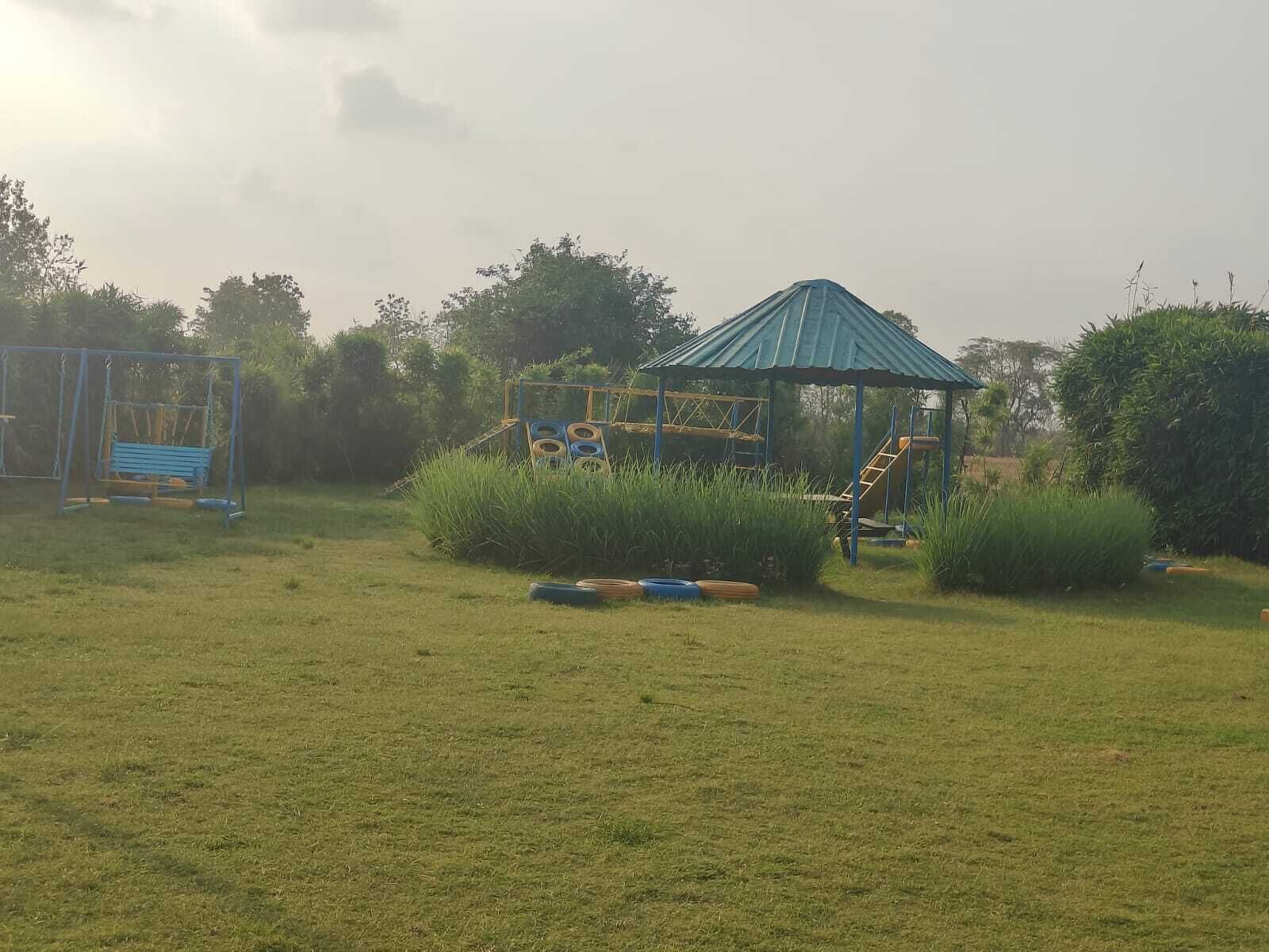 A playground with a blue-roofed shelter, a swing set, and a climbing structure.