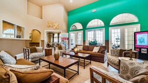 A spacious living area with a high ceiling, large windows, and a green accent wall. - Aco7947ha - Bella Vida Resort - 4 Bed 3 Baths Townhome (Kissimmee)