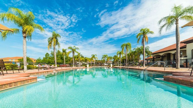 A clear swimming pool surrounded by palm trees and lounge chairs, with a clear blue sky above. - Aco7947ha - Bella Vida Resort - 4 Bed 3 Baths Townhome (Kissimmee)