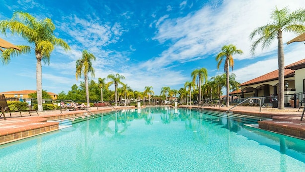 A clear swimming pool surrounded by palm trees and lounge chairs, with a clear blue sky above. - Aco7946ha - Bella Vida Resort - 6 Bed 5 Baths House (Kissimmee)