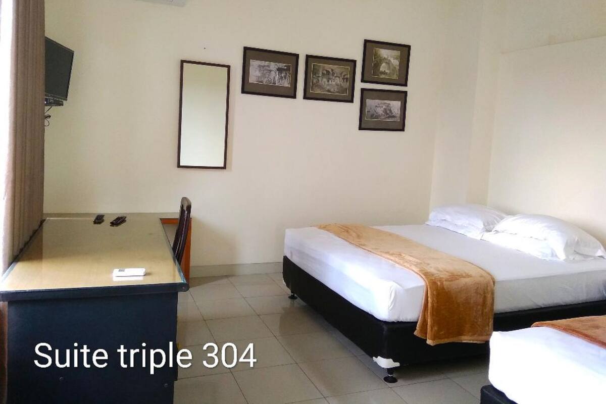 Una habitación de hotel con escritorio, cama y tres cuadros en la pared.