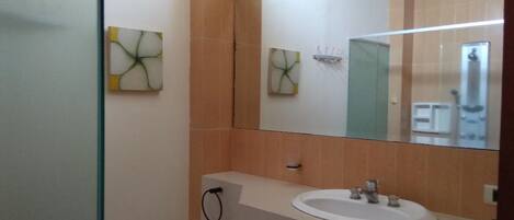 A bathroom with a white sink, a mirror, and two wall-mounted artworks.