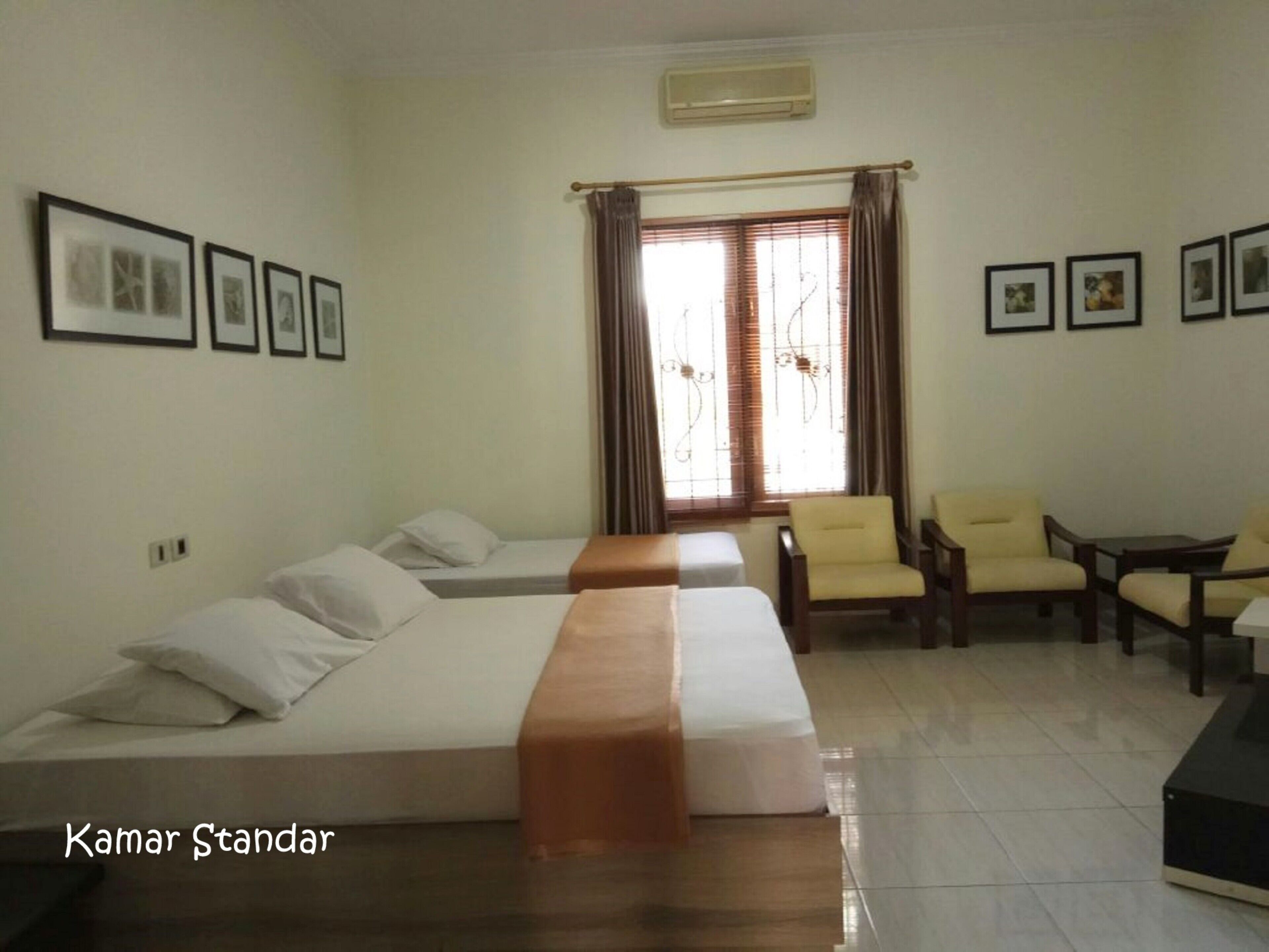 A hotel room with two beds, a sofa, and a seating area with chairs.