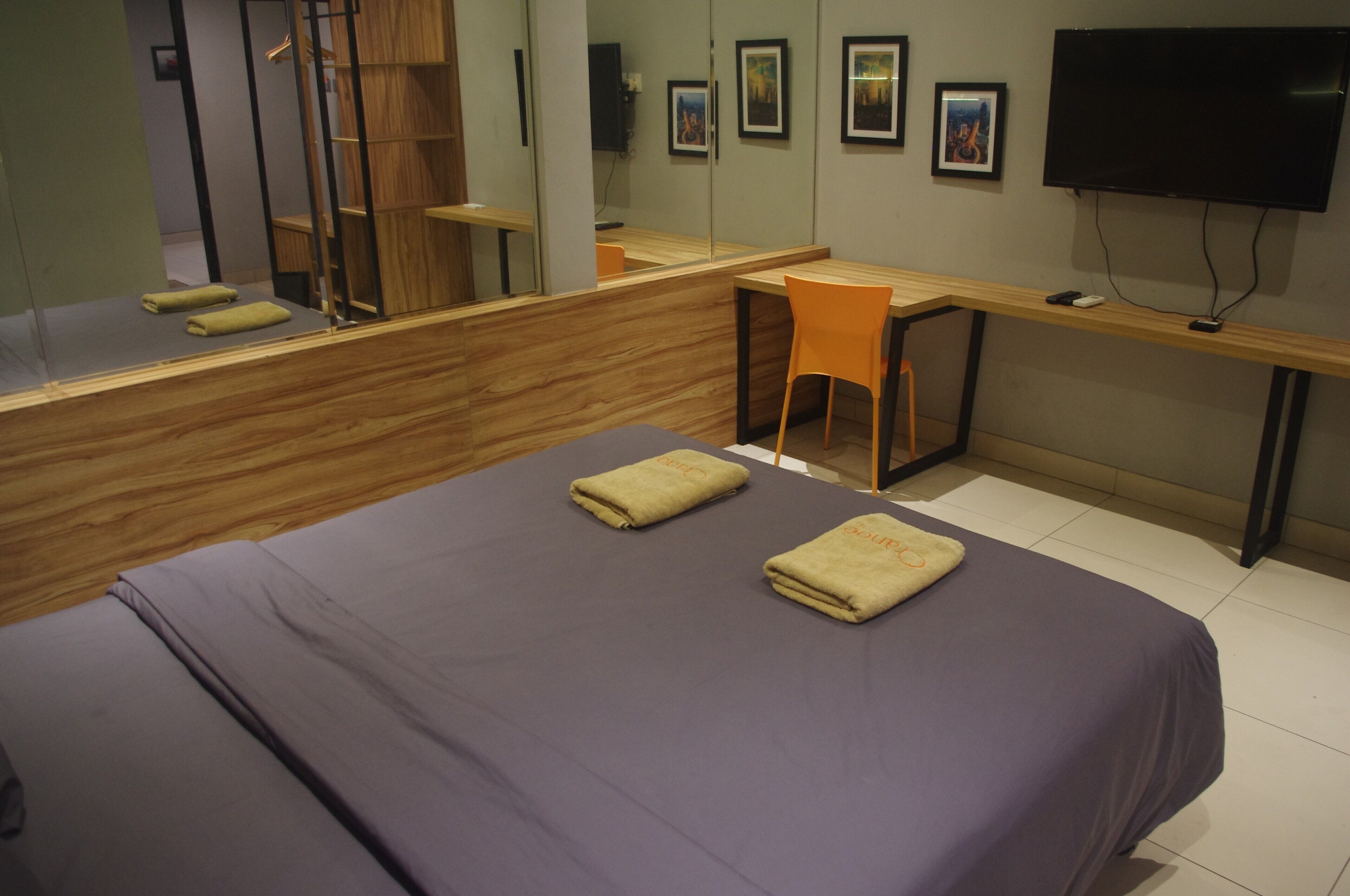 A hotel room with a bed, a desk, a chair, a television, and a mirror.