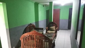 Una habitación con un sofá de madera, una silla, una mesita y una puerta al fondo.