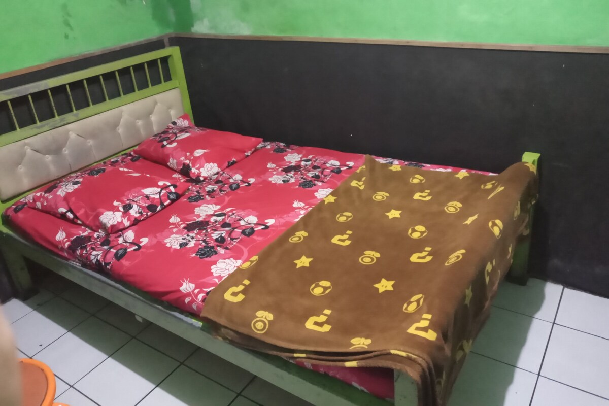 A single bed with a floral bedspread and a brown blanket with yellow patterns.