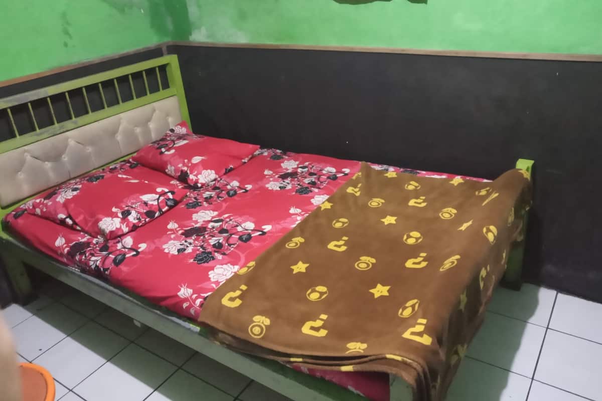 A single bed with a floral bedspread and a brown blanket with yellow patterns.
