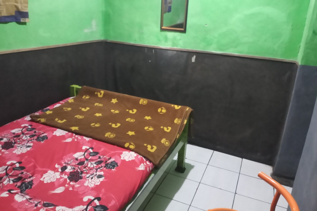 A room with a bed, a mirror on the wall, and a tiled floor.