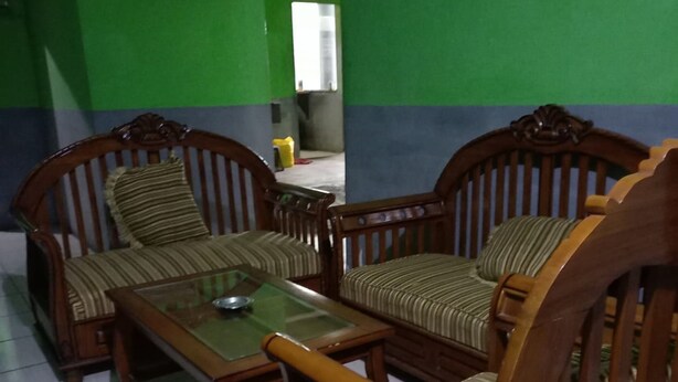 Una habitación con paredes verdes y azules, un conjunto de sofá de madera y una mesa de centro con superficie de vidrio.