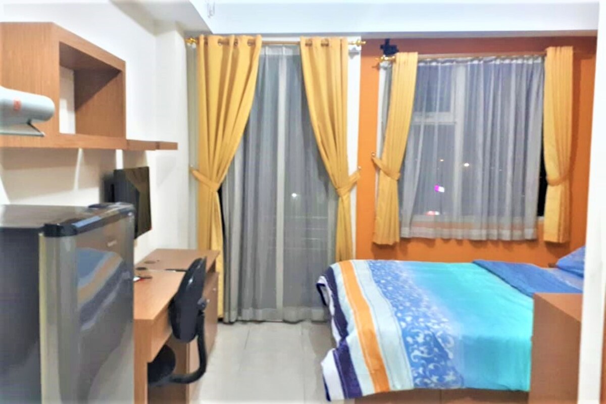 Una habitación de hotel con escritorio, silla, cama y cortinas.