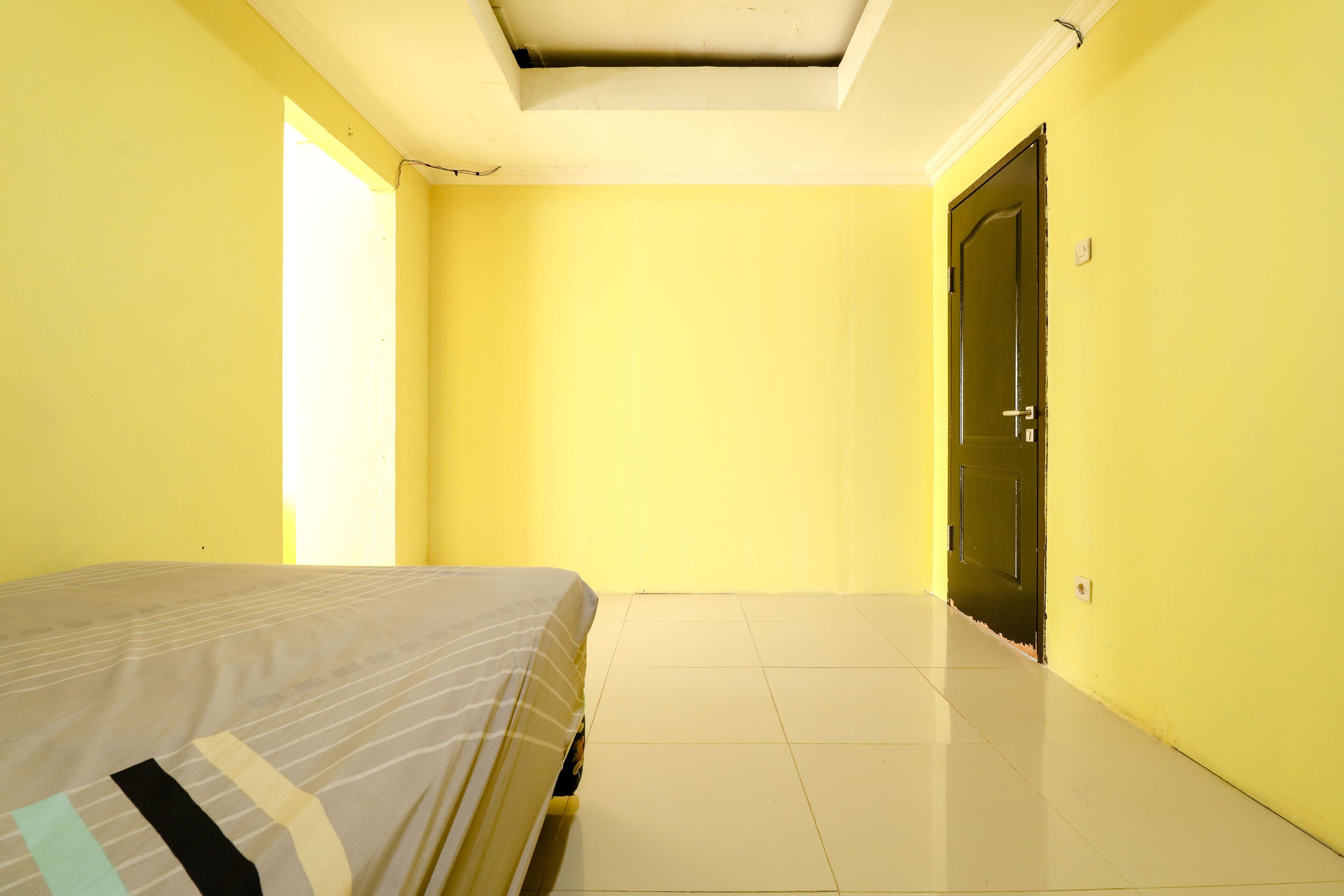 A room with a bed, a door, and a window.
