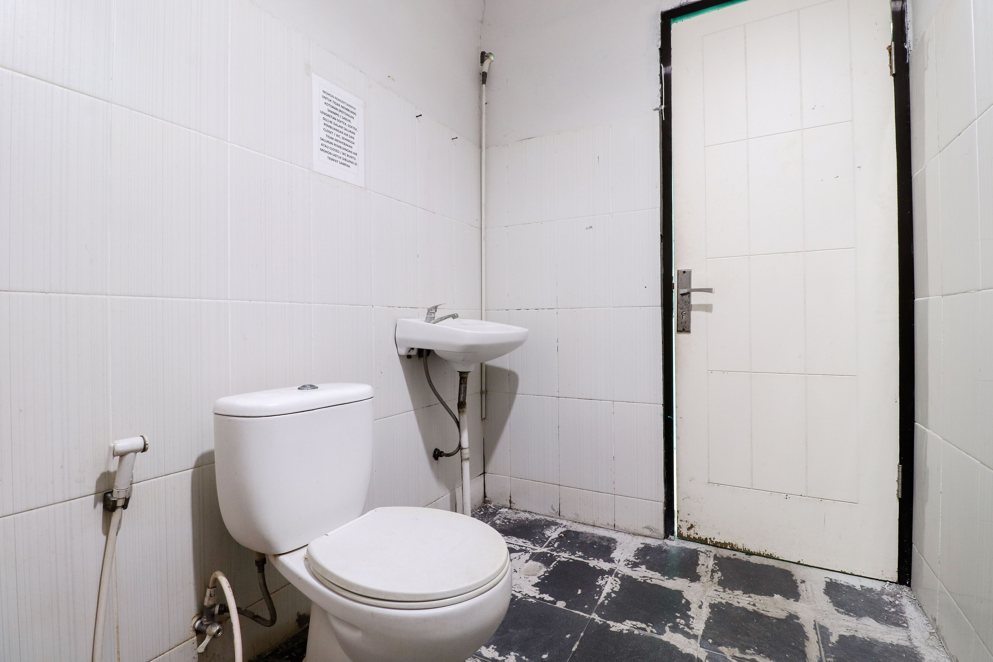 A small, basic bathroom with a toilet, sink, and a door.