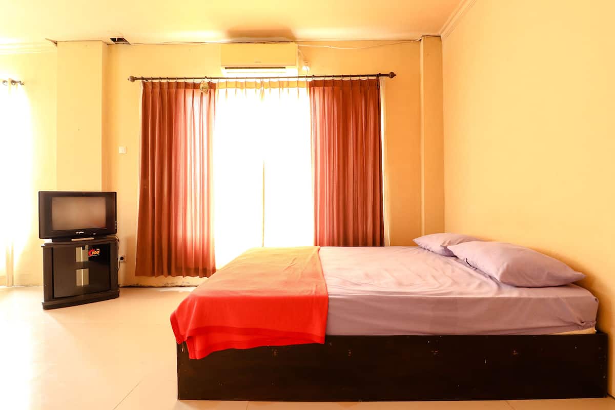 A bedroom with a bed, a television, and curtains.