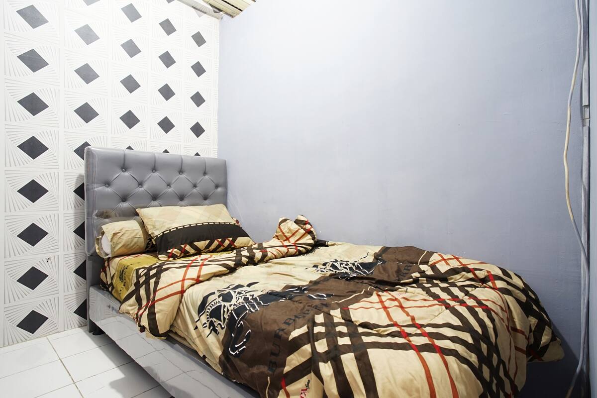 Una cama con cabecera capitonada, un muro con estampado y un muro liso con un cable a lo largo.