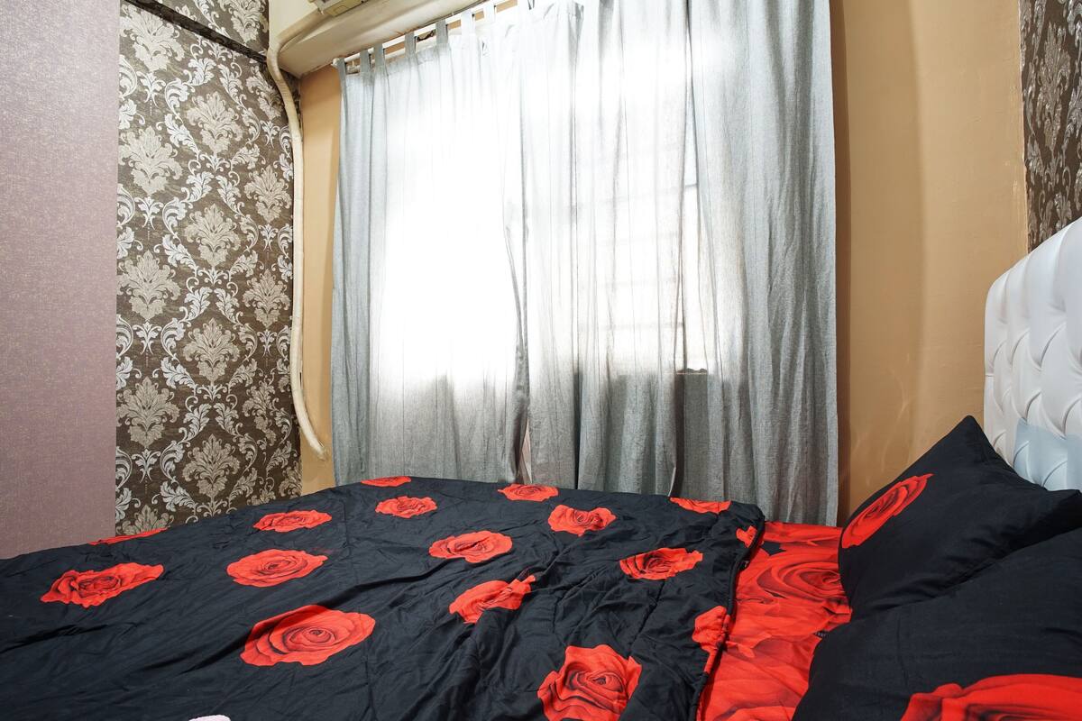Un dormitorio con cama, cortinas y papel tapiz estampado.