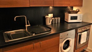 A kitchen with a sink, stove, microwave, and washing machine. - 55 St James Walk (Cheltenham)