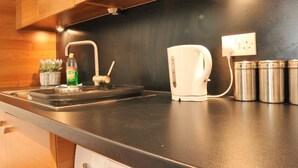 A kitchen with a black countertop, stainless steel appliances, and a sink. - 55 St James Walk (Cheltenham)