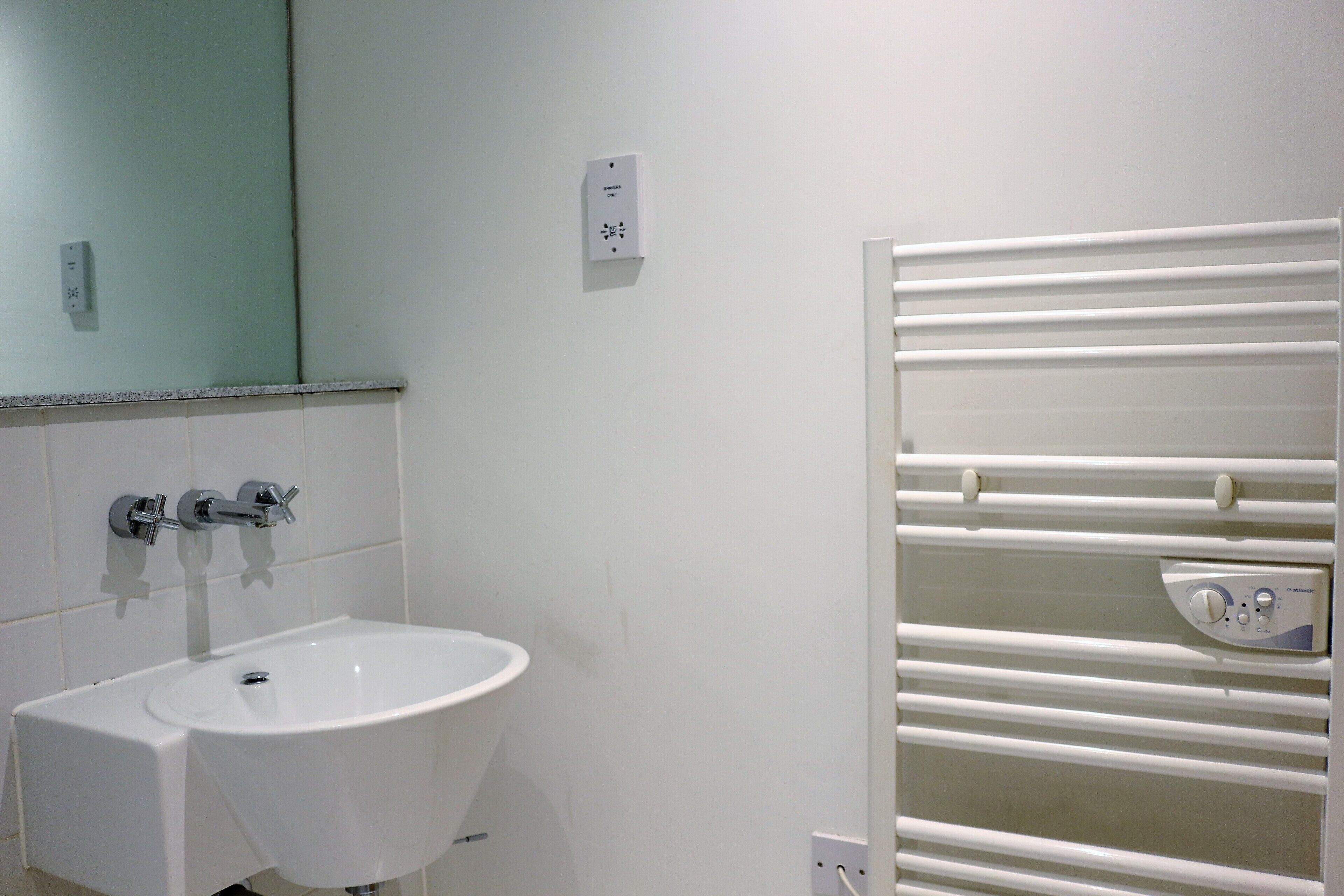 A bathroom with a white sink, a mirror, and a towel rack.