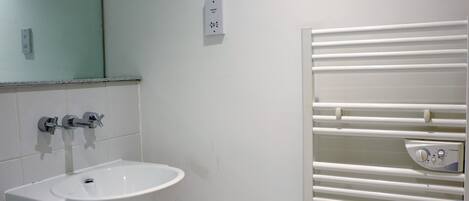 A bathroom with a white sink, a mirror, and a towel rack.