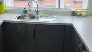 Una cocina con un lavaplatos doble, armarios y una ventana con vista a un edificio de ladrillo.