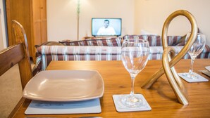 Una mesa de comedor con un plato, una copa de vino y un tenedor de madera.