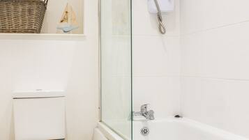 A bathroom with a toilet, a glass-enclosed shower, and a bathtub.