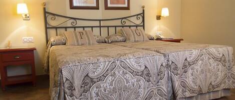 A double bed with a patterned bedspread, two bedside tables, and wall-mounted lamps.