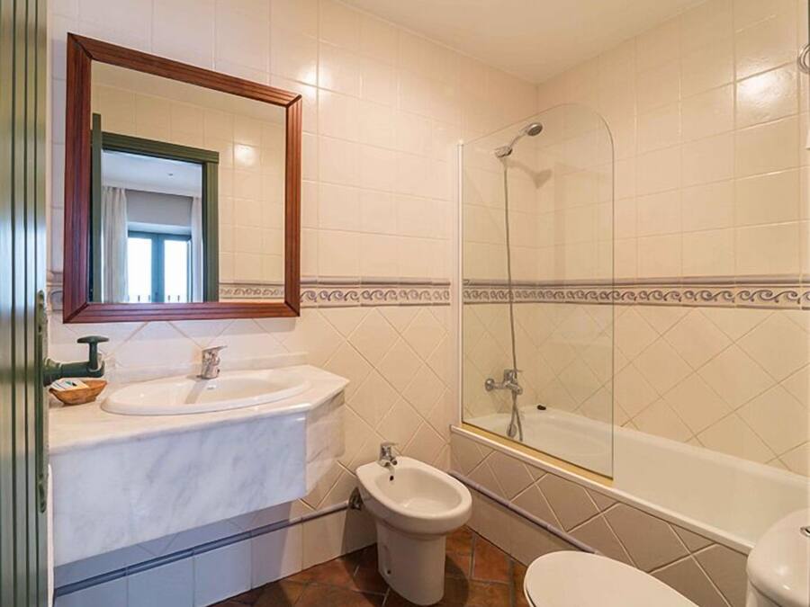 A bathroom with a sink, bidet, toilet, and a glass-enclosed shower.