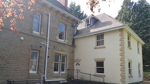 A two-story house with a stone facade and a white upper level. - Hillbrook House Apartment 9 (Malvern)