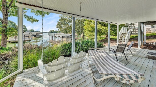 Une terrasse couverte avec un fauteuil suspendu, un hamac et une table avec des chaises.
