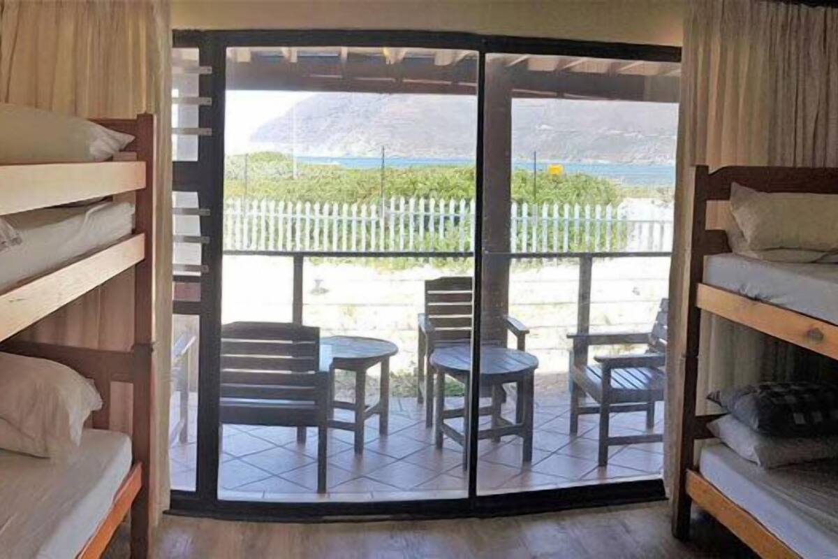 Habitació de dormitori amb llits superposats, una porta corredissa de vidre que dona a un patí exterior amb cadires i taula.