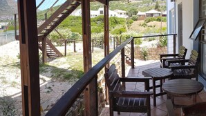 En balkon med træmøbler og udsigt over et bakket landskab.