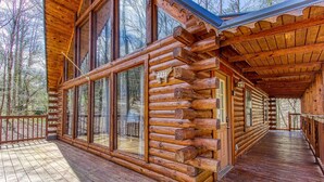 A log cabin with a wooden deck and large windows.