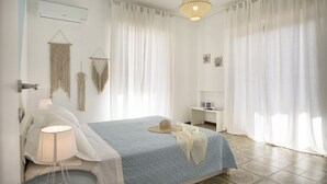 A bedroom with a bed, bedside table, lamp, and curtains.