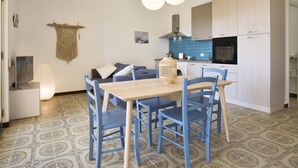 A modern kitchen with light wood cabinets, a blue tiled backsplash, and a central island with seating.