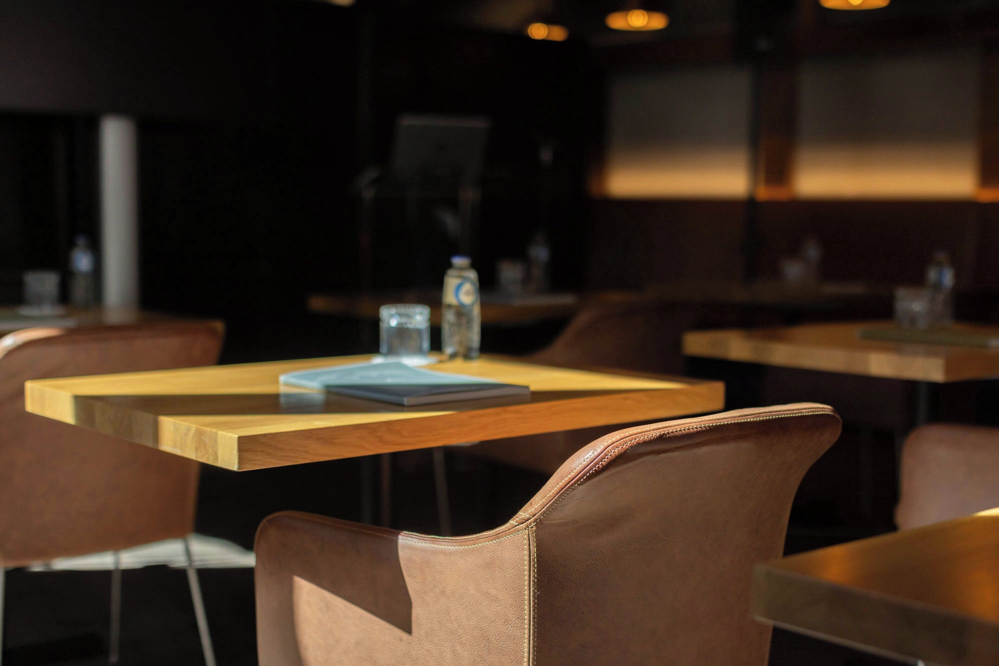 A restaurant interior with wooden tables and brown leather chairs.