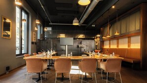 A modern conference room with a long table, four chairs, and overhead lighting. - Moxy Brussels City Center (Brussels)