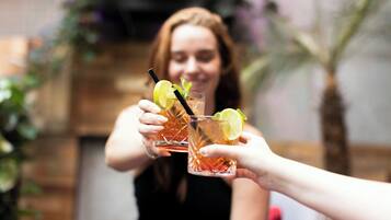 Dos personas sosteniendo vasos con bebidas, un trozo de lima y una pajita.