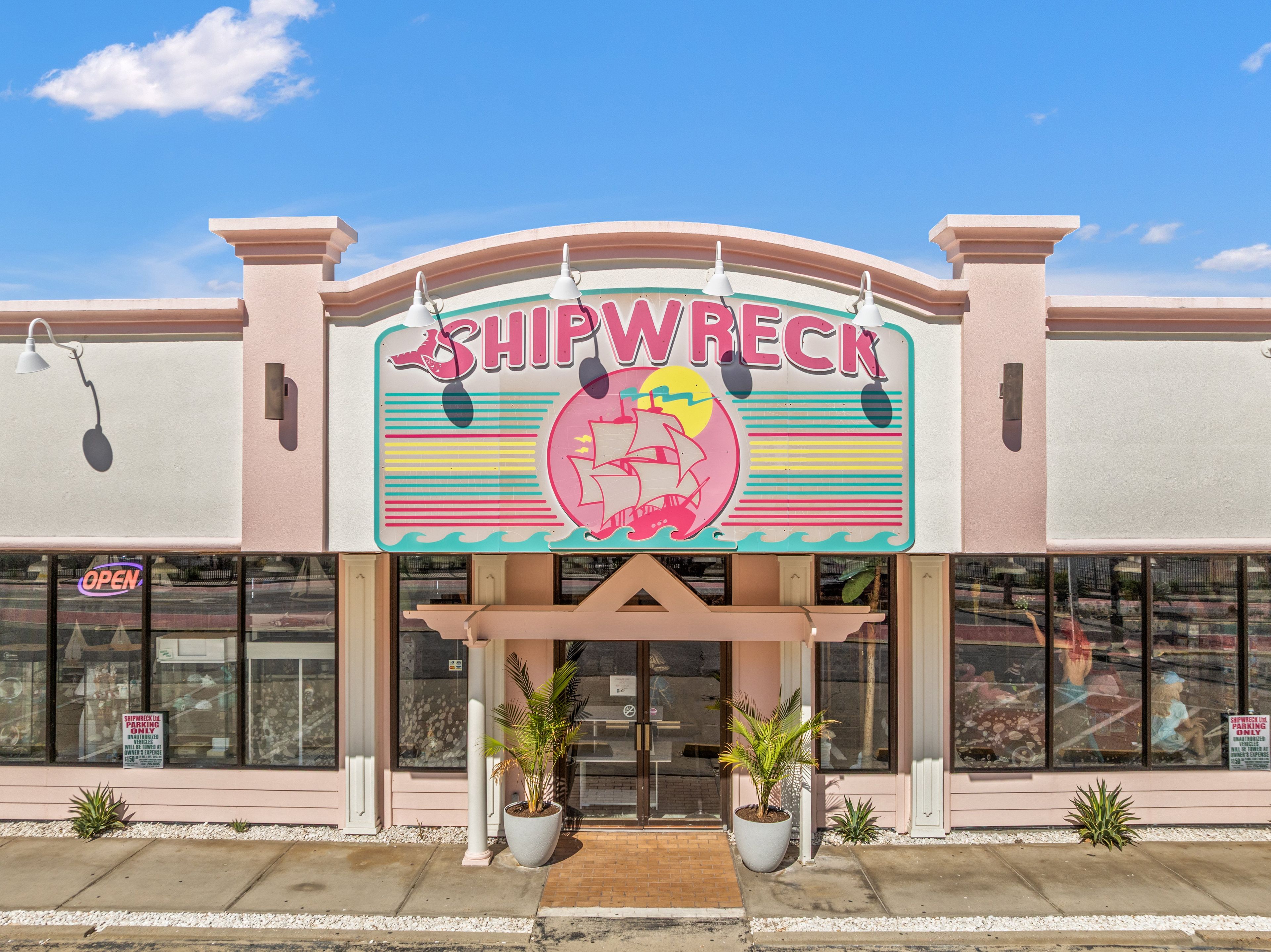 A storefront with a sign reading 'SHIPWRECK' and a neon 'OPEN' sign.