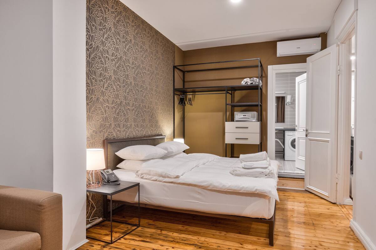 A neatly arranged hotel room with a bed, bedside table, lamp, and a wardrobe.