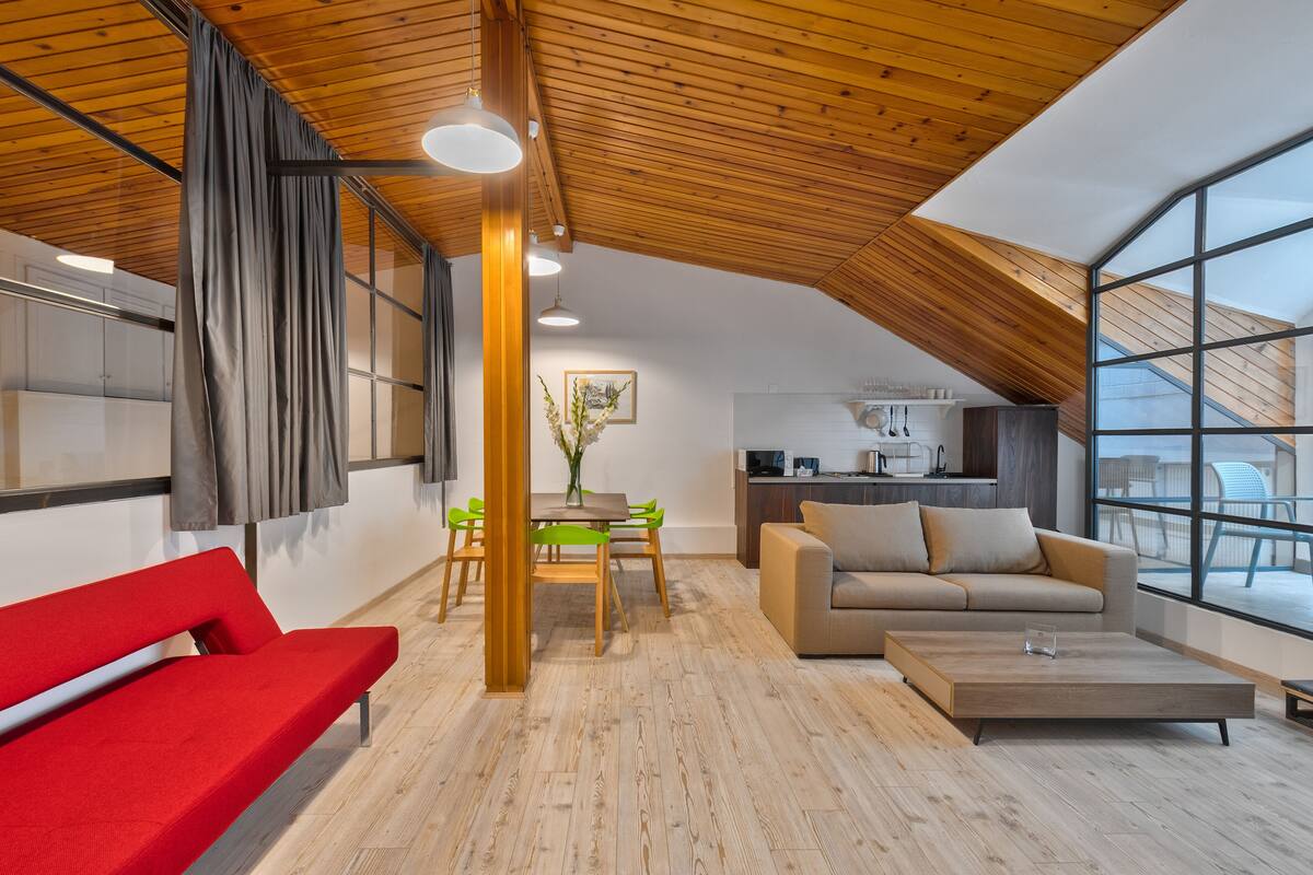 A modern interior with a dining area, a sofa, and a red bench.