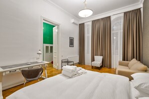 Een hotelkamer met een bed, een bureau, een stoel, een bank en uitzicht door het raam.