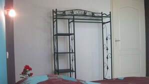 Quarto com estrutura de cama de metal, porta branca e colcha florida.
