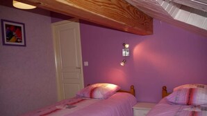 Um quarto com duas camas de solteiro, teto de madeira, porta branca e luminária fixada na parede.