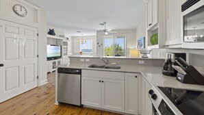 A modern kitchen with white cabinetry, a dishwasher, a stove, and a large window offering a view of the outdoors. - Townhome with stunning view of Matlacha Pass (Matlacha)